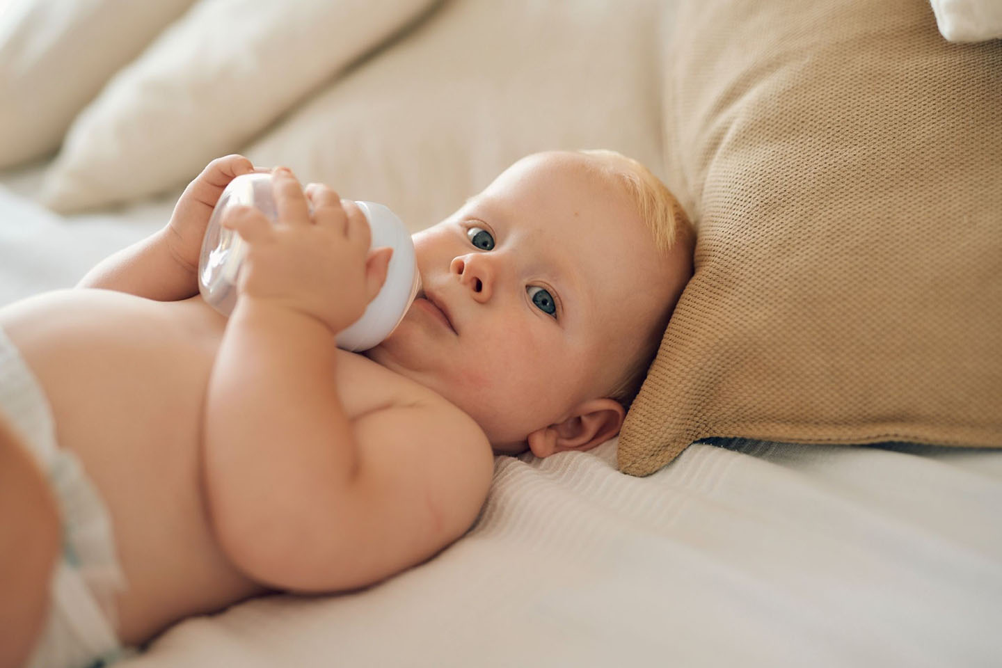 Diese Szene zeigt ein Baby, das auf dem Bett sitzt und eine Flasche in den Händen hält – ein wichtiger Schritt in Richtung selbstständigem Trinken. Das richtige Timing und die passende Menge beim Füttern aus der Flasche spielen eine große Rolle für die gesunde Entwicklung und das Wohlbefinden des Babys. Eltern können mit geeigneten Produkten und klaren Fütterungsrichtlinien sicherstellen, dass ihr Kind optimal versorgt wird.