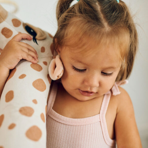 Ein Mädchen hält liebevoll ihre Plüschgiraffe – ein treuer Begleiter für die Kindheit.