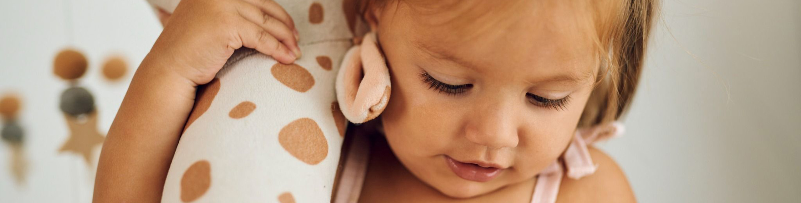 Diese Szene zeigt ein Mädchen, das eine Plüschgiraffe festhält. Für Kinder mit einer Allergie gegen Kuhmilcheiweiß ist eine angepasste Ernährung besonders wichtig. Die Darstellung verweist auf das Thema Allergien im Kindesalter und betont, wie wichtig sichere Alternativen und gut verträgliche Produkte für das Wohlbefinden betroffener Kinder sind.