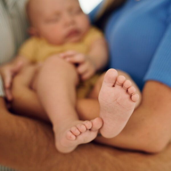 Caption: Ein Neugeborenes schläft friedlich im Arm der Eltern während des Stillens im Kinderzimmer.