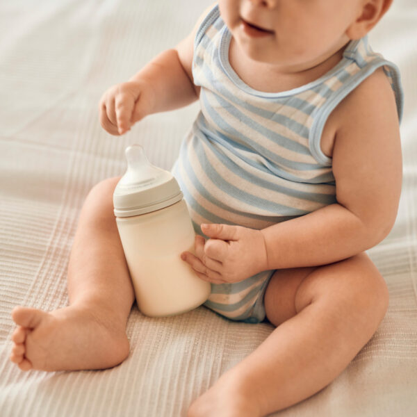 Diese Szene zeigt ein Baby, das auf dem Bett sitzt und eine Flasche Novalac Milch in den Händen hält. Der Moment symbolisiert Selbstständigkeit und Neugier, während das Baby seine Mahlzeit genießt. Novalac bietet hochwertige Formeln, die die gesunde Entwicklung und die Verdauung des Babys optimal unterstützen.