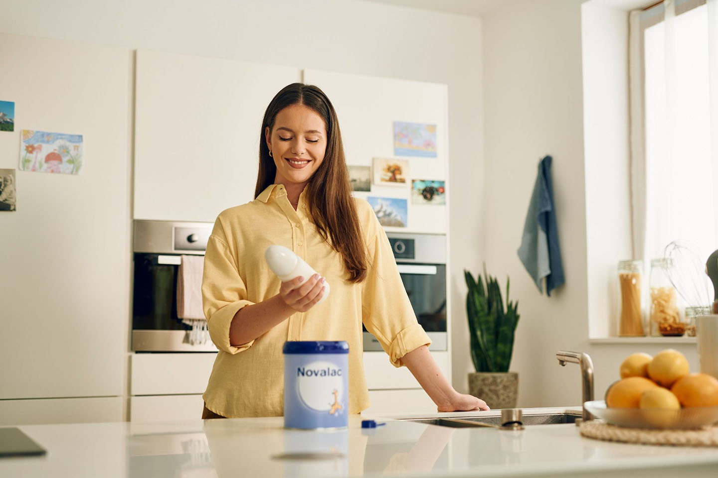 Mutter bereitet in der Küche eine Milchflasche zu – Hinweis auf Kuhmilcheiweißallergie