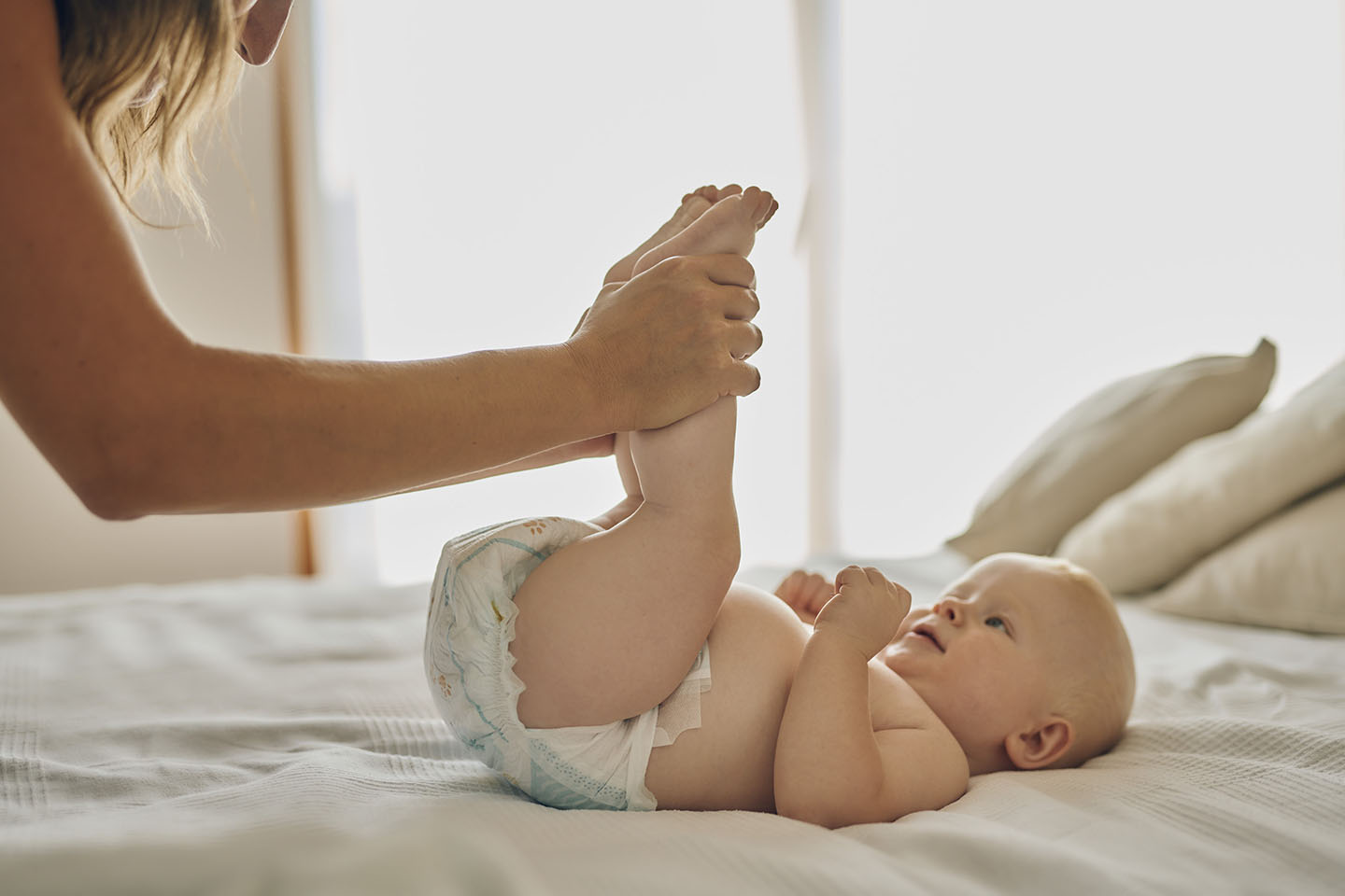 Ein Baby wird während des Windelwechsels bei Verstopfung von den Eltern unterstützt – mit Novalac.