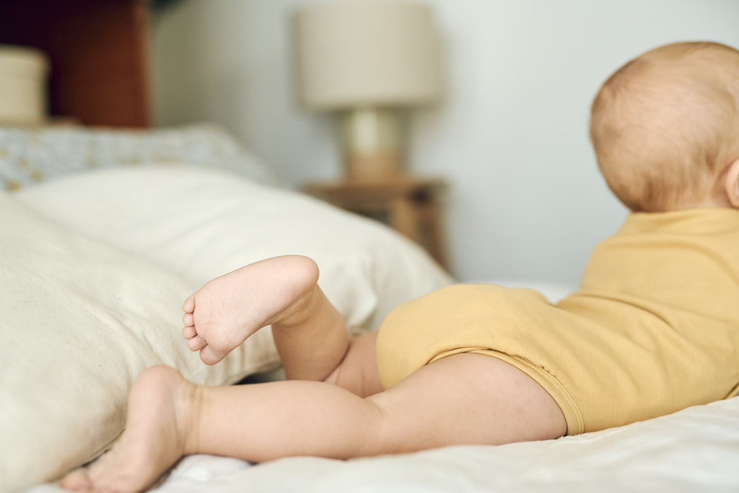 Ein Baby mit Koliken liegt auf dem Bett und wird durch Novalac unterstützt.