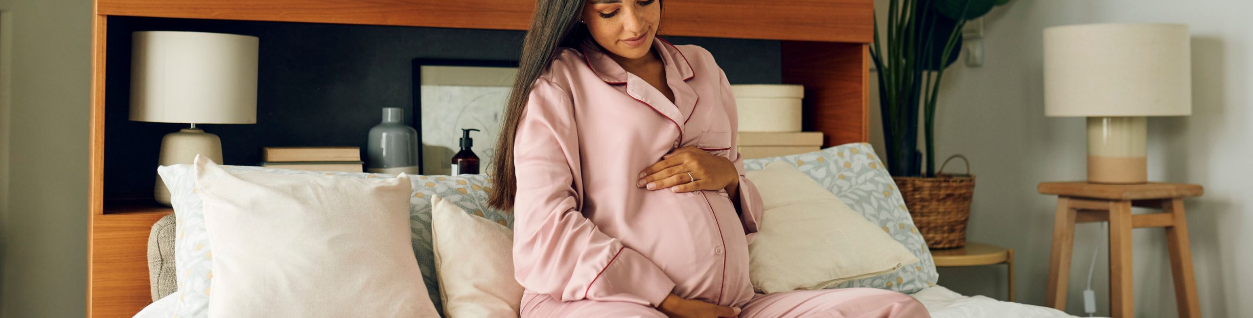 Diese Szene zeigt eine schwangere Frau, die im Bett sitzt und liebevoll ihren Bauch berührt. Der Moment unterstreicht, wie entscheidend Vitamine und Mineralstoffe während der Schwangerschaft sind, um die gesunde Entwicklung des Babys zu unterstützen. Eine ausgewogene Versorgung mit Folsäure, Eisen, DHA und anderen wichtigen Nährstoffen trägt wesentlich zum Wohlbefinden von Mutter und Kind bei.