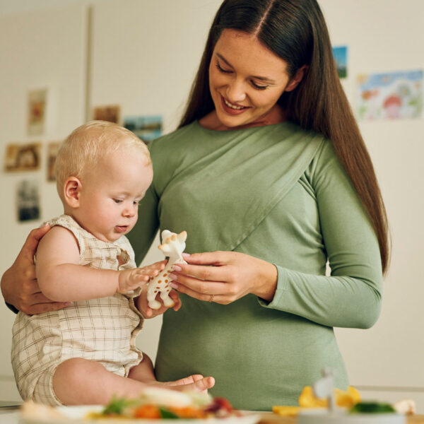 Eine Mutter und ihr Baby genießen unbeschwerte Momente in der Küche mit einer beliebten Giraffe, ganz ohne Sorgen über Allergien.