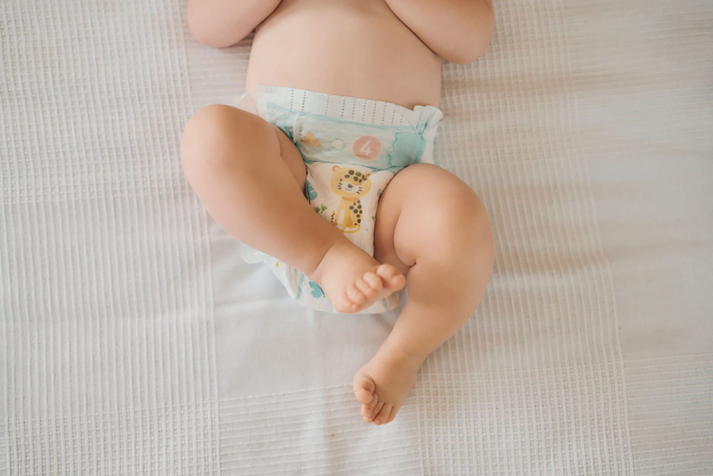 Diese Szene zeigt ein Baby, das aufgrund von Verstopfung auf dem Bett liegt und seine Beine gekreuzt hält – eine typische Haltung bei Bauchbeschwerden. Verstopfung ist bei Säuglingen häufig und kann zu Unruhe und Unwohlsein führen. Die richtige Ernährung und sanfte Unterstützung helfen, die Verdauung zu regulieren und das Wohlbefinden des Babys zu verbessern.