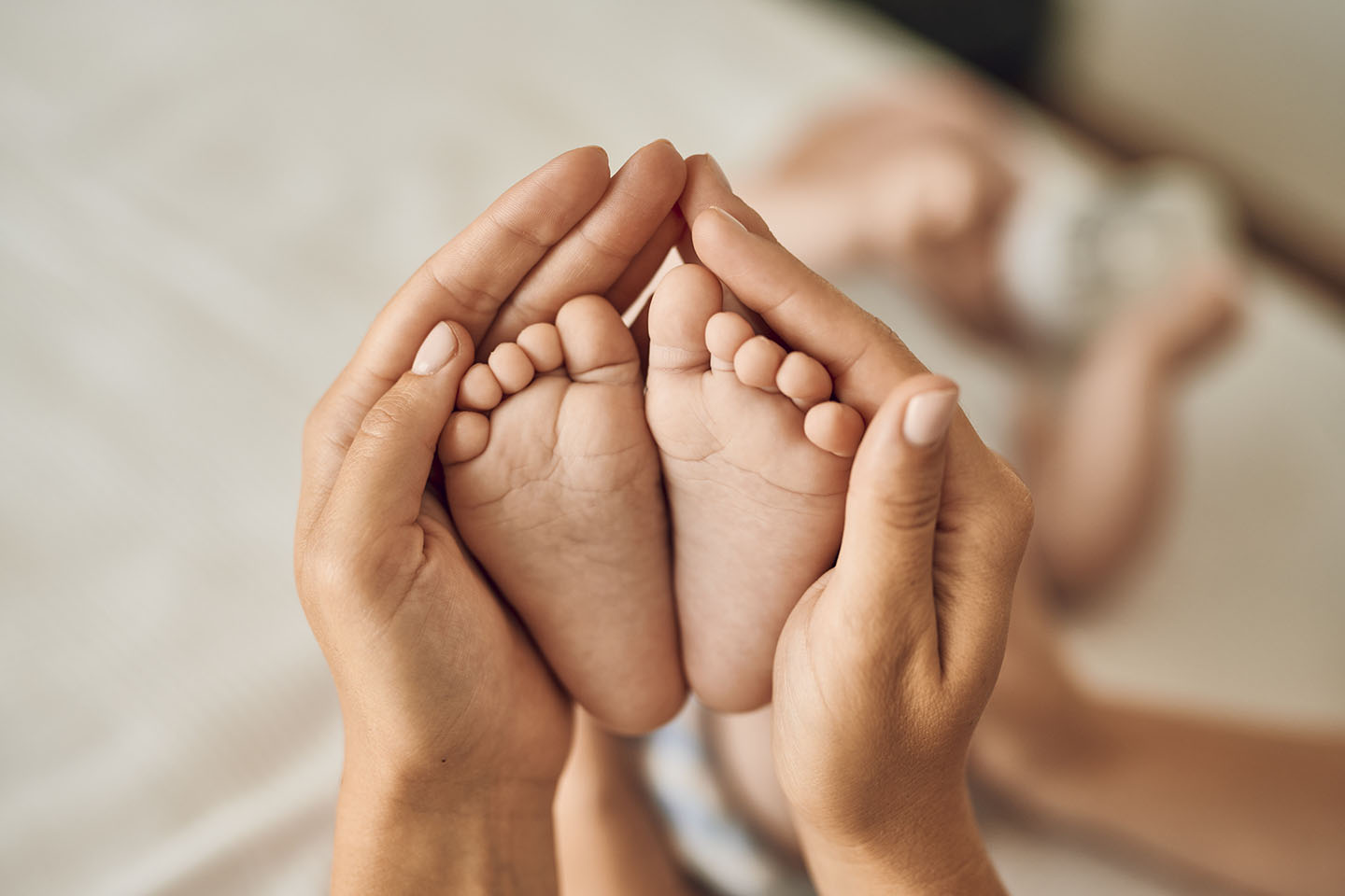 Diese Szene zeigt die kleinen Beine und Füße eines Babys, das sicher im Arm der Mutter liegt. Der Moment vermittelt Wärme, Nähe und Geborgenheit – wichtige Elemente für die emotionale Entwicklung in den ersten Lebensmonaten.