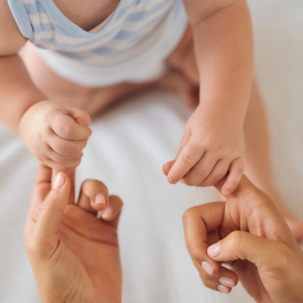 Ein Baby hält die Finger seiner Mutter – ein besonderer Moment der Verbindung.