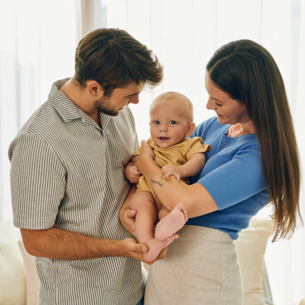 Eltern genießen einen glücklichen Moment zu Hause, während sie ihr Baby im Arm halten.