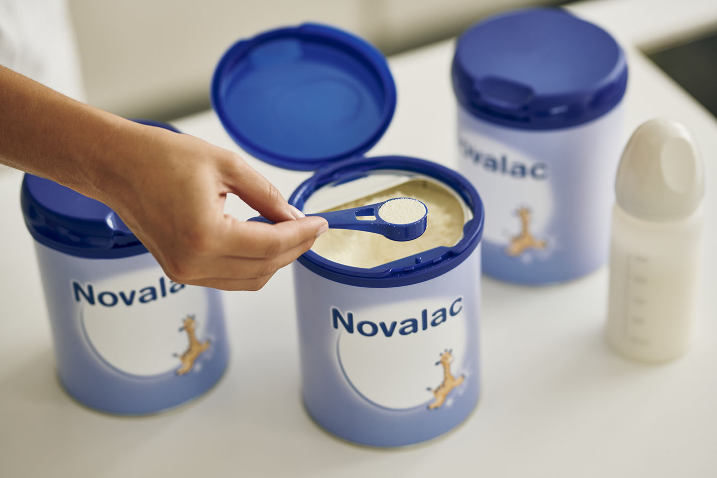 Diese Szene zeigt die sorgfältige Dosierung der Novalac Ersatzmilch. Die genaue Menge an Pulver und Wasser gewährleistet eine ausgewogene, sichere Mahlzeit für das Baby. Präzise Zubereitung ist wichtig, um den Nährstoffgehalt zu erhalten und die Verdauung des Babys optimal zu unterstützen.