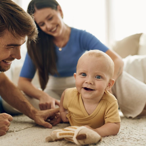 Diese Szene zeigt eine glückliche junge Familie, bestehend aus Vater, Mutter und ihrem Baby. Solche gemeinsamen Augenblicke stärken die familiäre Bindung und schaffen eine liebevolle, sichere Umgebung, die für die Entwicklung des Babys besonders wichtig ist.