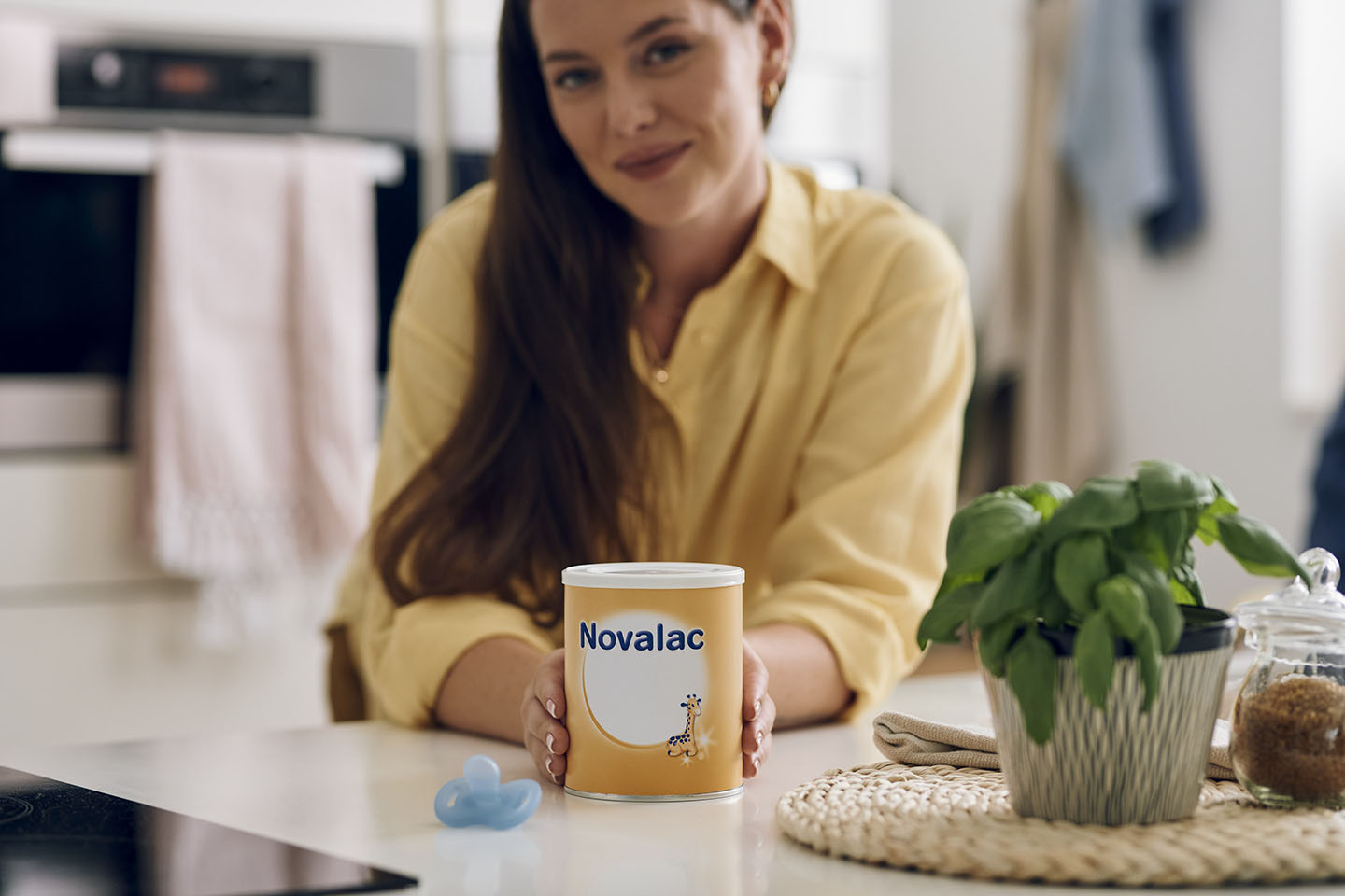 Diese Szene zeigt eine lächelnde Mutter, die eine Dose Novalac Säuglingsnahrung in der Hand hält. Der Moment vermittelt Vertrauen, Zufriedenheit und Sicherheit bei der Wahl der richtigen Ernährung für ihr Baby. Novalac Formeln sind sorgfältig entwickelt, um die Verdauung zu unterstützen und den Nährstoffbedarf von Säuglingen optimal zu decken.