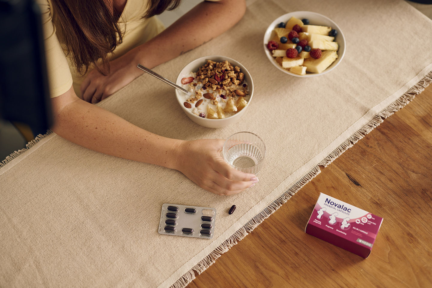 Diese Szene zeigt eine Frau, die ein ausgewogenes Frühstück mit Müsli und einem Glas Wasser einnimmt, ergänzt durch Novalac Prenatal Kapseln. Die Kombination aus Nährstoffen aus dem Frühstück und essentiellen Vitaminen wie Folsäure, Eisen und DHA aus den Kapseln unterstützt werdende Mütter optimal. Ein nährstoffreicher Start in den Tag trägt zu einer gesunden Schwangerschaft und zum Wohlbefinden von Mutter und Baby bei.