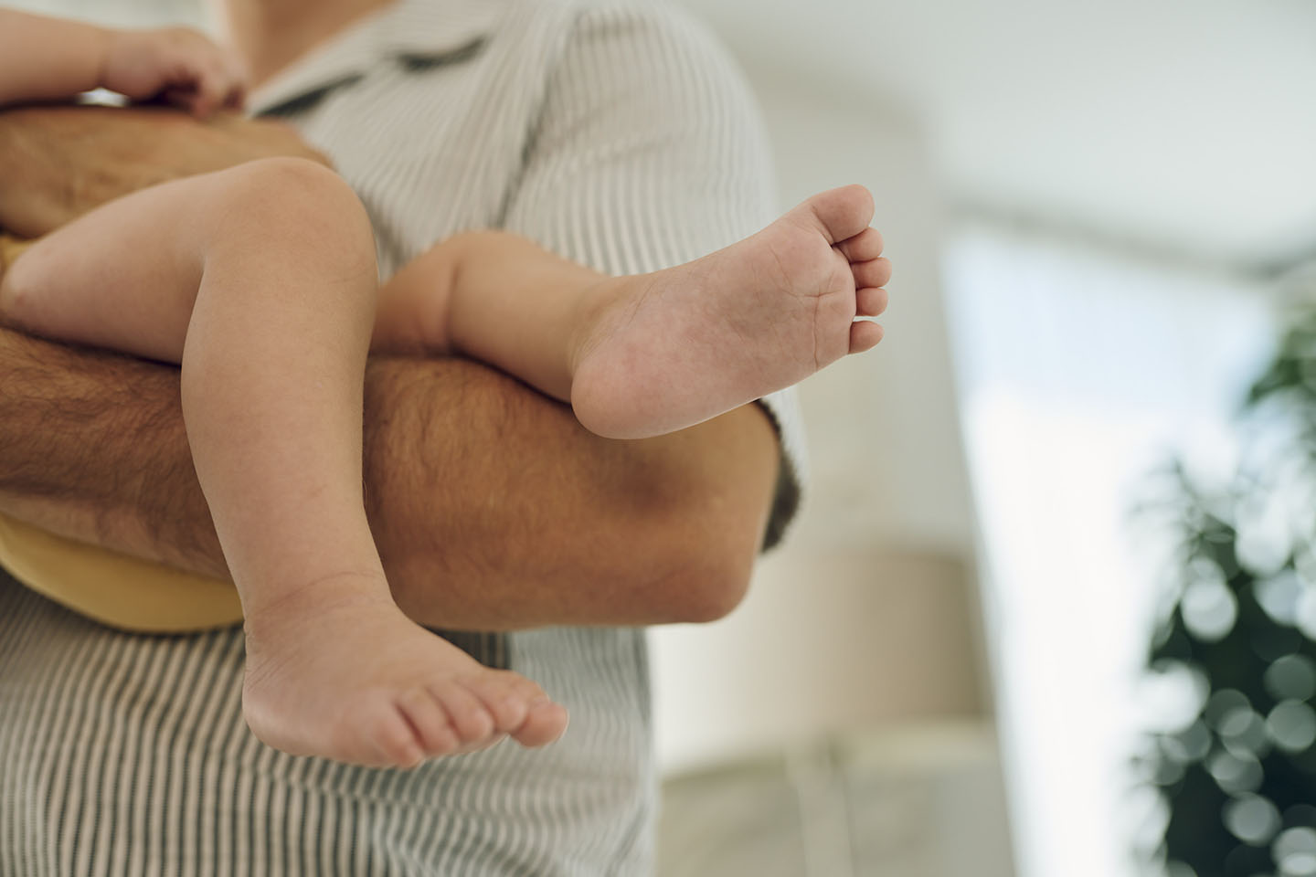 Diese Szene zeigt einen Babyfuß, der liebevoll von den Händen der Eltern umschlossen wird – ein Symbol für Schutz, Nähe und Geborgenheit. Solche innigen Momente stärken die emotionale Bindung und schaffen eine warme, sichere Umgebung für das Neugeborene.