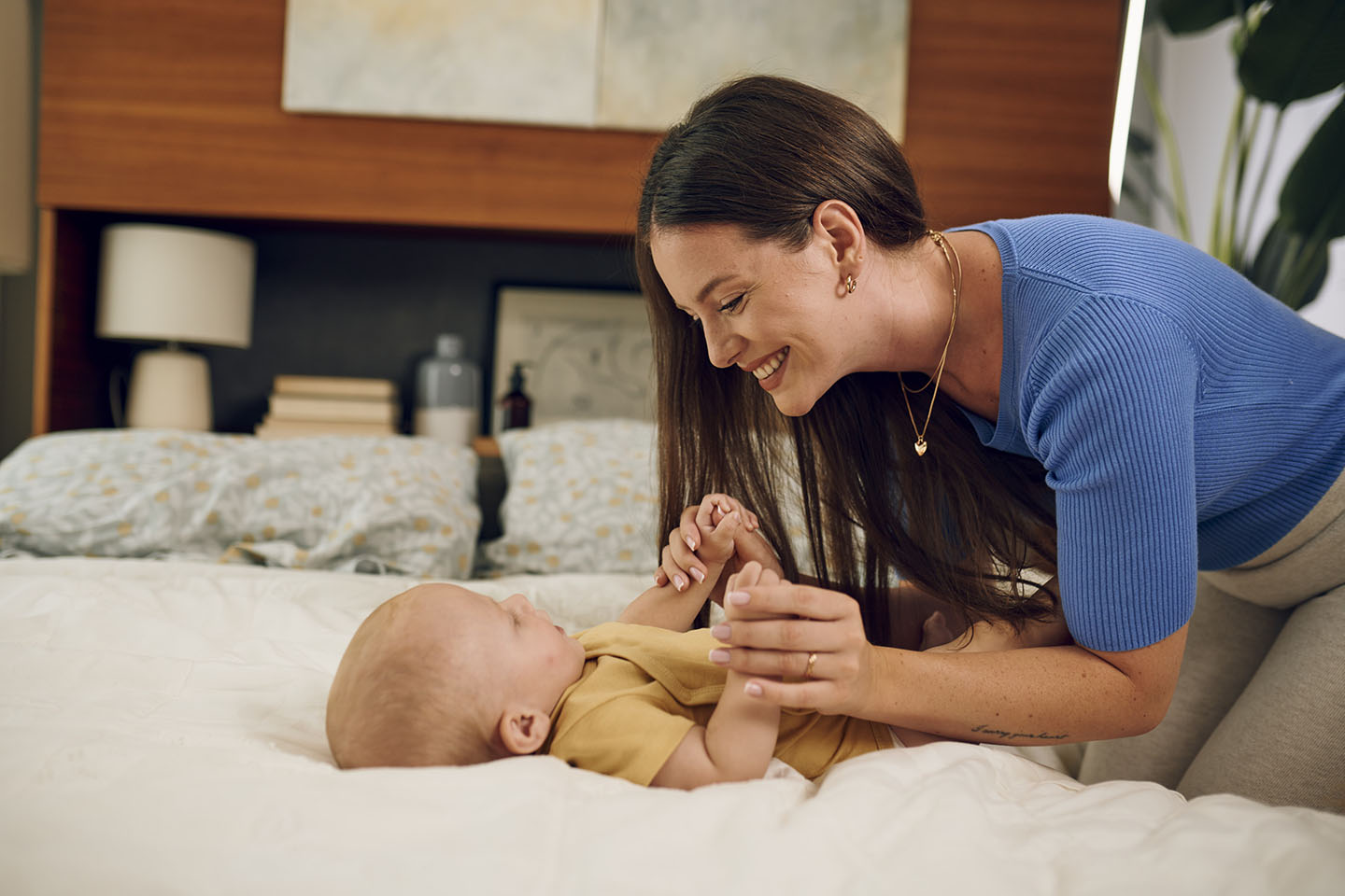 Diese Szene zeigt eine Mutter, die mit ihrem Baby auf dem Bett spielt – ein Moment voller Nähe, Freude und Bindung. Solche gemeinsamen Augenblicke fördern die emotionale Entwicklung des Babys und schaffen eine warme, sichere Umgebung, in der es sich geborgen fühlt.