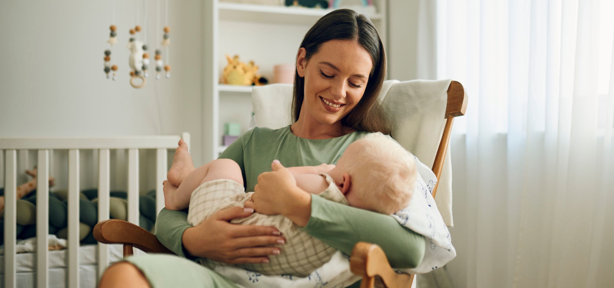 Eine Mutter hält ihr Baby im Arm und bereitet sich auf das Stillen nach der Geburt vor.
