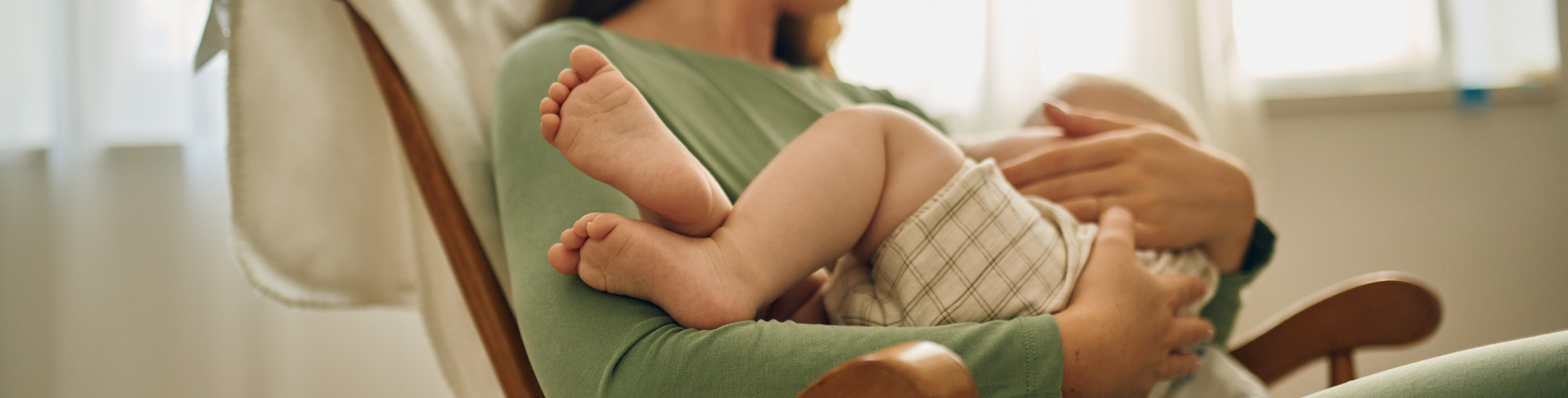 Diese Szene zeigt eine Mutter, die ihr Baby im Kinderzimmer stillt – ein Moment voller Nähe, Ruhe und Geborgenheit. Stillen unterstützt nicht nur die Ernährung und das Immunsystem des Babys, sondern stärkt auch die emotionale Bindung zwischen Mutter und Kind in den ersten Lebensmonaten.