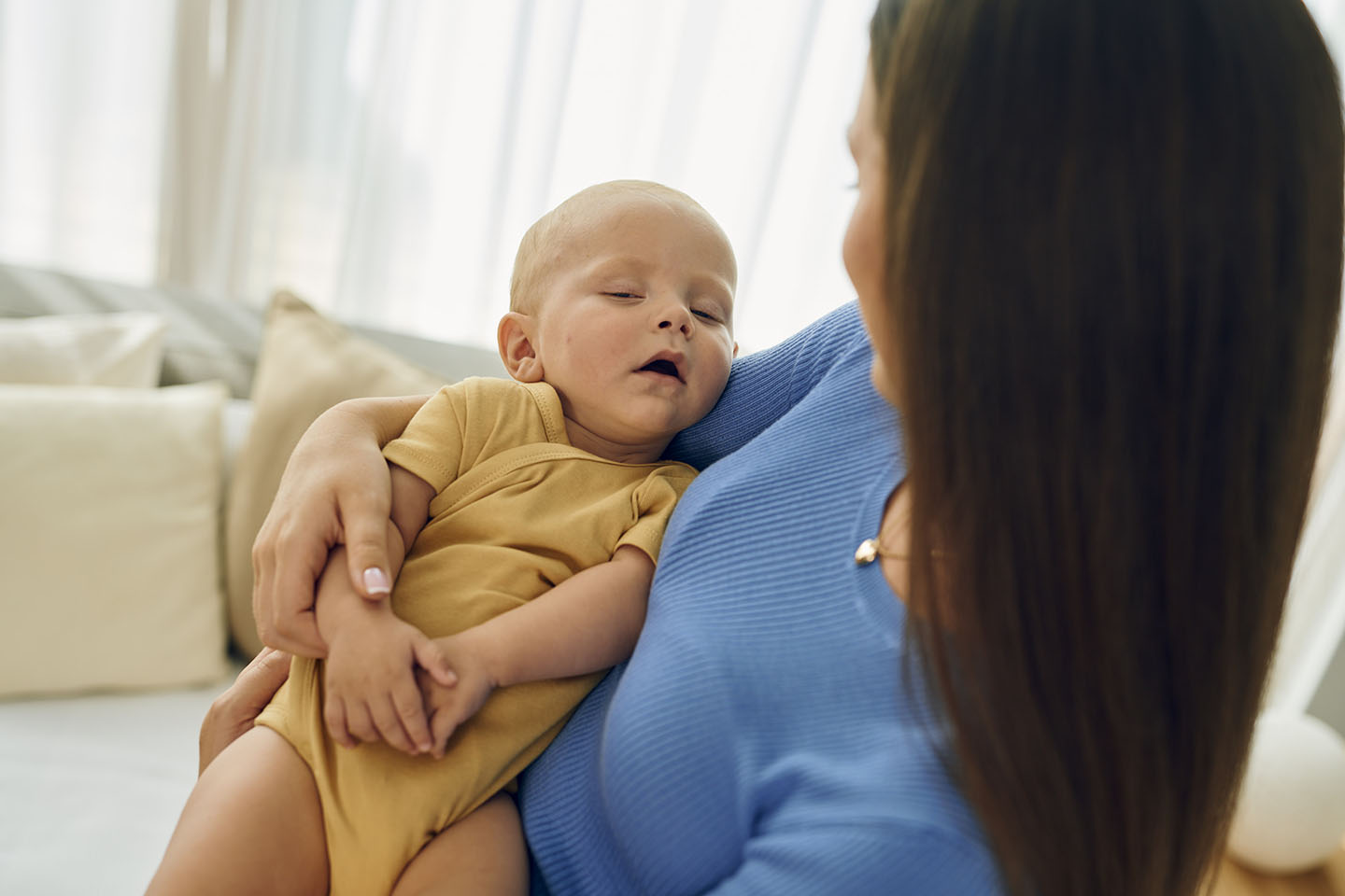 Diese Szene zeigt eine Mutter, die ihr schlafendes Kind liebevoll im Arm hält. Solche ruhigen, zärtlichen Momente stärken die emotionale Bindung, vermitteln Sicherheit und unterstützen das Wohlbefinden des Kindes.