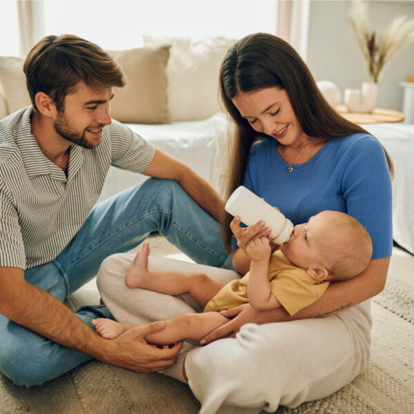 Diese Szene zeigt eine Familie, die ihr Baby in einer komfortablen Wohnzimmerumgebung mit einer Novalac Flasche füttert. Solche ruhigen, liebevollen Momente unterstützen die Bindung und schaffen eine sichere Atmosphäre für das Baby. Die Verwendung einer hochwertigen Novalac Formel sorgt für eine ausgewogene und gut verträgliche Mahlzeit, die das gesunde Wachstum und Wohlbefinden des Kindes fördert.