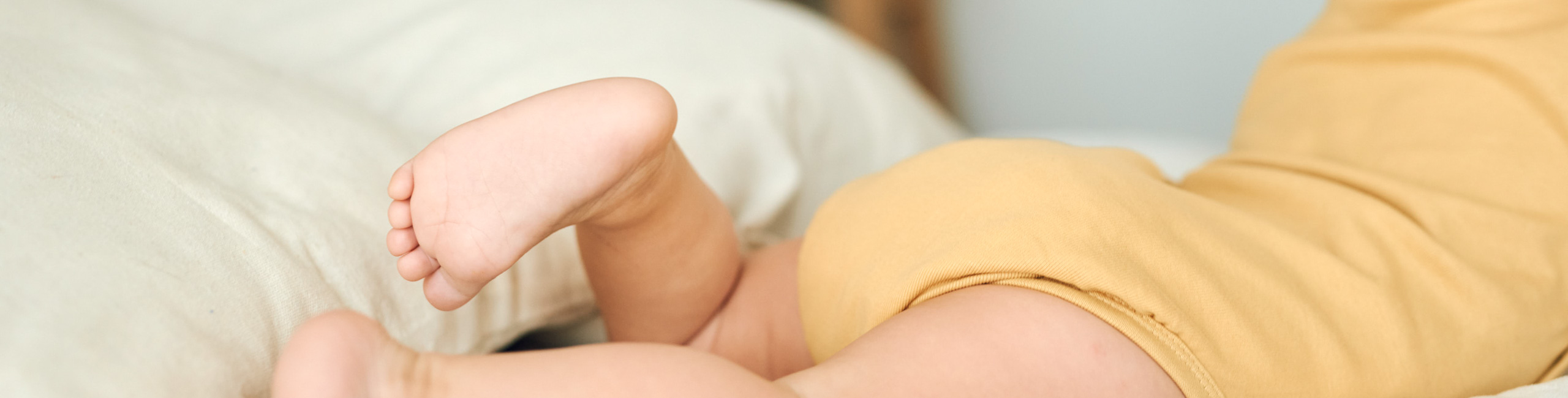 Diese Szene zeigt ein Baby, das aufgrund von Verstopfung auf dem Bett liegt und seine Beine gekreuzt hält – eine typische Haltung bei Bauchbeschwerden. Verstopfung ist bei Säuglingen häufig und kann zu Unruhe und Unwohlsein führen. Die richtige Ernährung und sanfte Unterstützung helfen, die Verdauung zu regulieren und das Wohlbefinden des Babys zu verbessern.