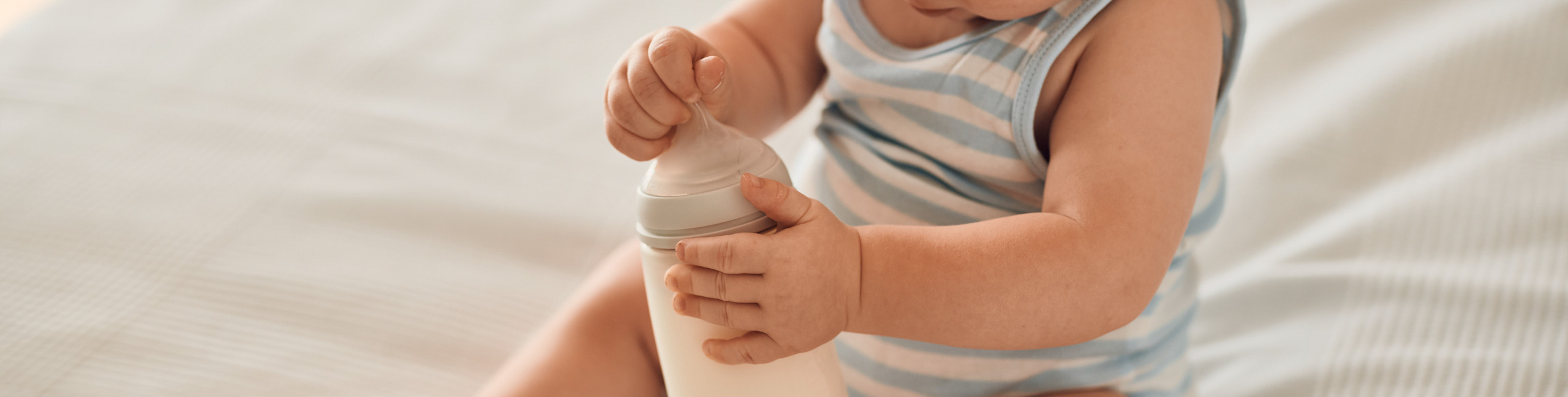 Diese Szene zeigt ein Baby, das auf dem Bett sitzt und eine Flasche in den Händen hält – ein wichtiger Schritt in Richtung selbstständigem Trinken. Das richtige Timing und die passende Menge beim Füttern aus der Flasche spielen eine große Rolle für die gesunde Entwicklung und das Wohlbefinden des Babys. Eltern können mit geeigneten Produkten und klaren Fütterungsrichtlinien sicherstellen, dass ihr Kind optimal versorgt wird.