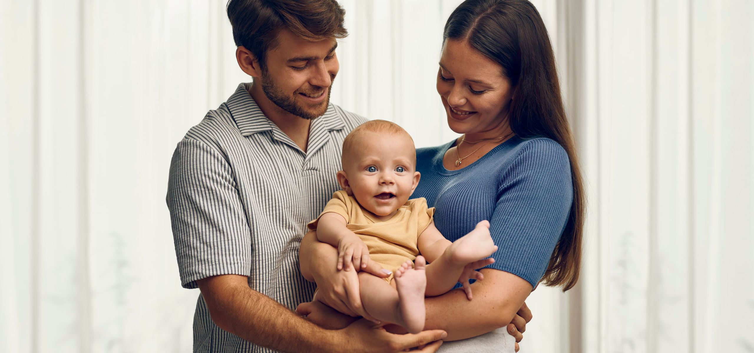 Majka i otac drže bebu u naručju, sretna obitelj